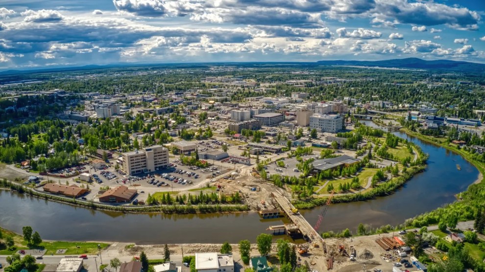 An aerial shot of the city of Fairbanks, encircled by a river under a blue sky.